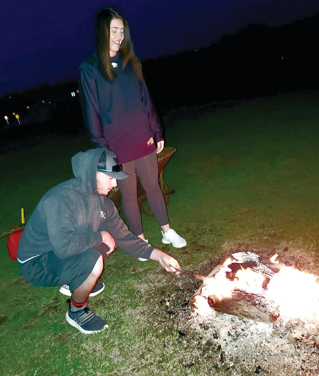 Blake Wibberg and Abby Klebba enjoy time around a fire.